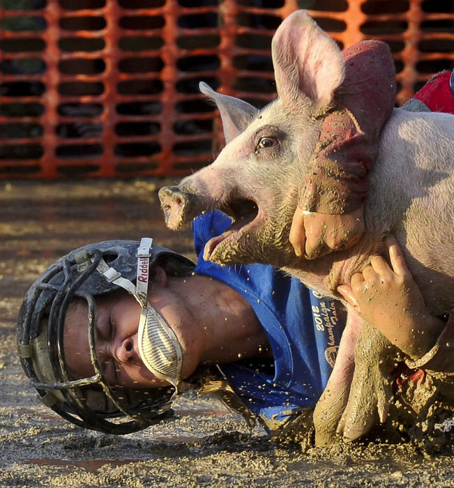 First place, Photographer of the Year - Small Market - Bill Lackey / Springfield News-SunA pig squeels as a competitor in the Champaign County Fair Pig Scramble jumps on its back Sunday. The group of girls, competing in the scramble, run through the mud as they try to catch one of several juvenile pigs loose in a pin and drag the mud covered pig into a center ring. Those competitors who succeed, get to raise the pig and bring it to the fair next year to show and sell.  