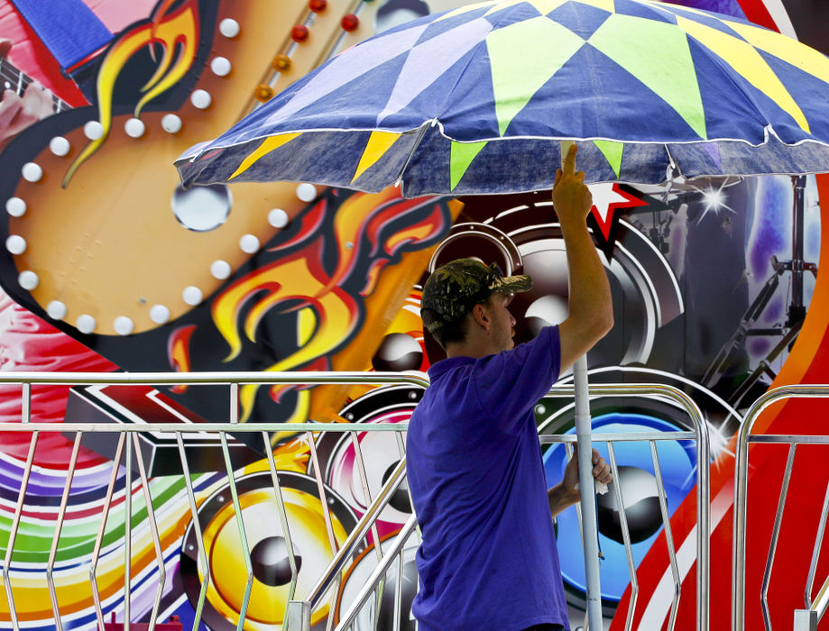 Second place, Photographer of the Year - Small Market - Barbara J. Perenic / Springfield News-SunA midway worker raises an umbrella before the rides opened to the public at noon at the county fair.