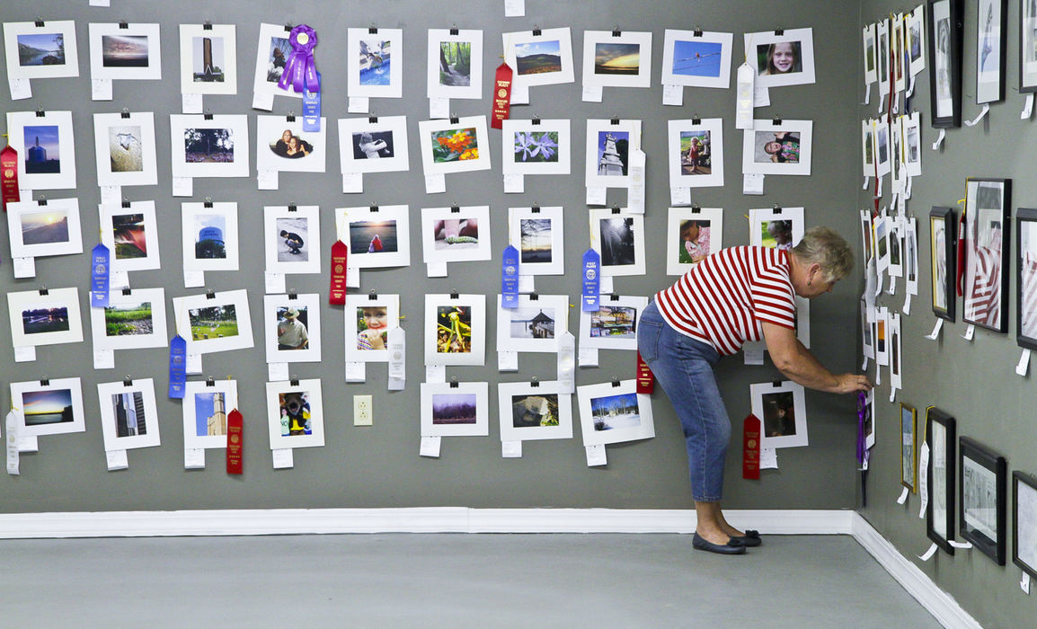 Second place, Photographer of the Year - Small Market - Barbara J. Perenic / Springfield News-SunKris Harmon places ribbons on the winning photographs after the fine arts entries were judged under the grandstand.