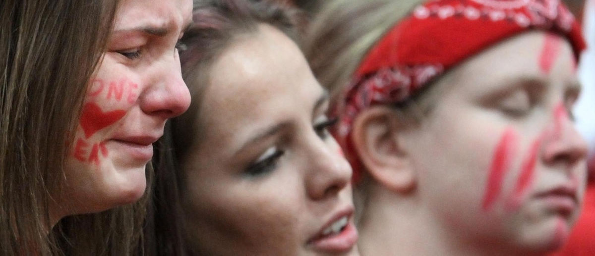 Award of Excellence, Sports Portfolio - John Kuntz / The Plain DealerSeniors Maggie Williams (L) and Bianca Mandato (C) along with other Chardon High School students react sadly to the singing of the National Anthem as they watch their team line up arm-in-arm with their opponents from Madison High School March 1, 2012 during a Division I sectional semifinal game at Euclid High School. 