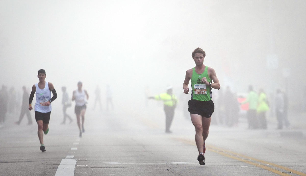 Award of Excellence, Sports Portfolio - Eamon Queeney / The Columbus DispatchMatt Lemon, of Vandalia, right, emerges from the fog as he makes his way to the 9-mile marker during the Columbus Marathon Sunday morning, October 21, 2012. Lemon ran the half marathon in 1:08:36, good for 9th place. The annual Columbus Marathon packed 18,000 runners and walkers into the full and half marathons that snaked through the city on a cool and foggy fall morning. This year the Nationwide Children's Hospital was named the title beneficiary and at each mile there was a "patient champion;" 26 children, each with a life-altering story of disease. 