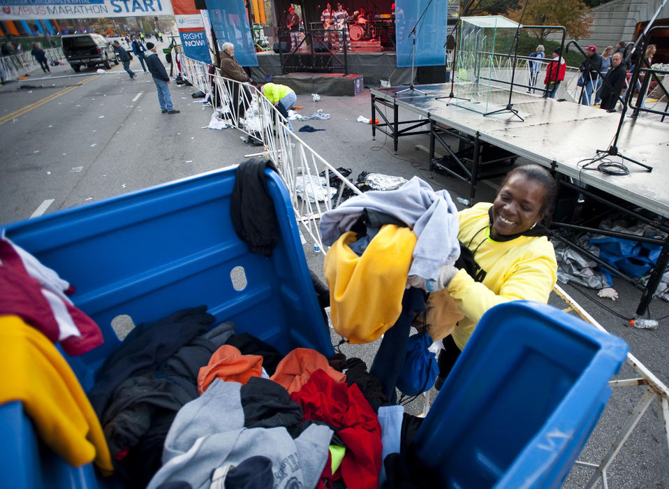 Award of Excellence, Sports Portfolio - Eamon Queeney / The Columbus DispatchVolunteer Tenisa Smith, of Columbus, loads a Goodwill bin full of clothes that were discarded during the beginning of the Columbus Marathon Sunday morning, October 21, 2012. Goodwill volunteers were collecting the discarded clothes to recycle for re-sale in Goodwill stores. The annual Columbus Marathon packed 18,000 runners and walkers into the full and half marathons that snaked through the city on a cool and foggy fall morning. This year the Nationwide Children's Hospital was named the title beneficiary and at each mile there was a "patient champion;" 26 children, each with a life-altering story of disease. 
