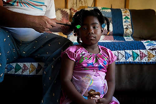 First place, Student Photographer of the Year - Meg Roussos / Ohio University Azaria gets one of her braids redone by her Dad. Barney explains that he learned through some books and YouTube how to take care of her African American hair. “We do her hair every 2-3 weeks and it is a total process,” said Barney.  “This among other things are going to be a challenge because she doesn’t have a female in her family.”