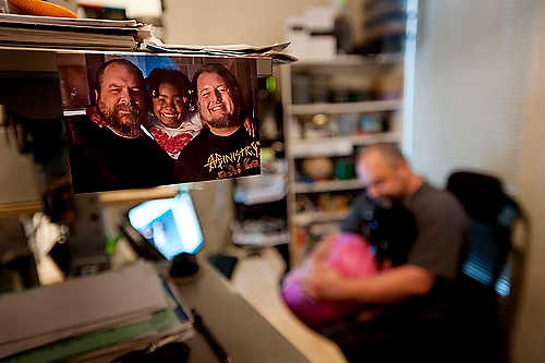 First place, Student Photographer of the Year - Meg Roussos / Ohio University A picture of the Stauffer-Barney family hangs in their office as Stauffer and Azaria cuddle during the workday. The couple work from home, Barney works for a French software company and Stauffer works for Cisco. They have been married twice, once in 2004 and again in 2008 due to legal issue with gay marriage. Barney and Stauffer adopted Azaria officially last winter, but have been fostering her for the past two years.