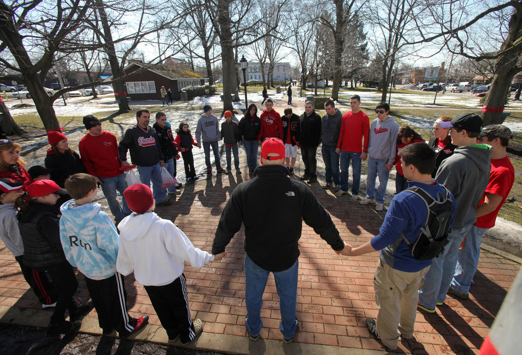 First place, Team Picture Story - Thomas Ondrey / The Plain DealerThe day after the shooting, a group of students and parents gathered for a prayer on Chardon Square before setting out to tie red ribbons on trees, utility poles and porches. The school's colors are red and black.  The small, tight-knit community came together in numerous ways to support one another after the tragedy.  (Thomas Ondrey/The Plain Dealer)