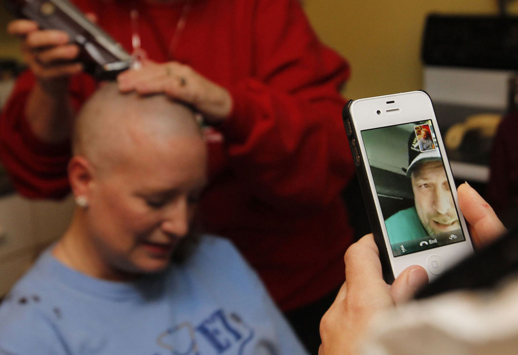 Award of Excellence, Feature Picture Story - Karen Schiely / Akron Beacon JournalHarry Schock watches via smart phone as his wife, Michelle Lang-Schock has her head shaved by her mother Lin Lang-Tyler at the Schocks' apartment. Schock, a truck driver, was out of town when friends and family members gathered to show their support. 