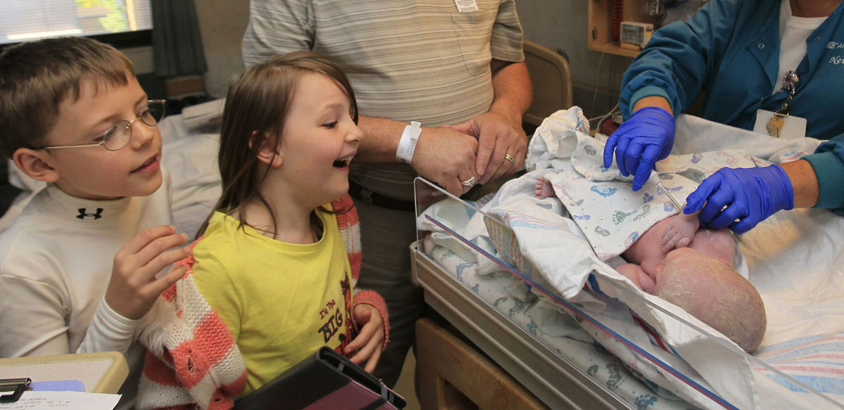Award of Excellence, Feature Picture Story - Karen Schiely / Akron Beacon JournalMax Wertman, 9 (left) and his sister Bella, 7, react to seeing their sister Chali Schock for the first time as she is being tended to by labor and deliver nurse Nanette Salomone after her birth at the Akron General Medical Center. 