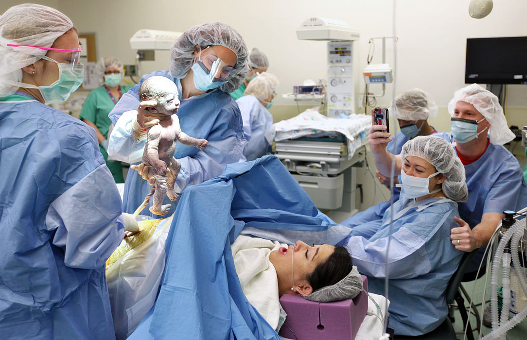 First Place, Feature Picture Story - Chris Russell / The Columbus Dispatch Dr. Jaina Lindauer presents the first of two twin boys delivered by cesarian section to Chrissy Knott while her sister Annie Johnston and her husband Joby and Chrissy's husband James look on at Riverside Hospital's Women's Health Center.   