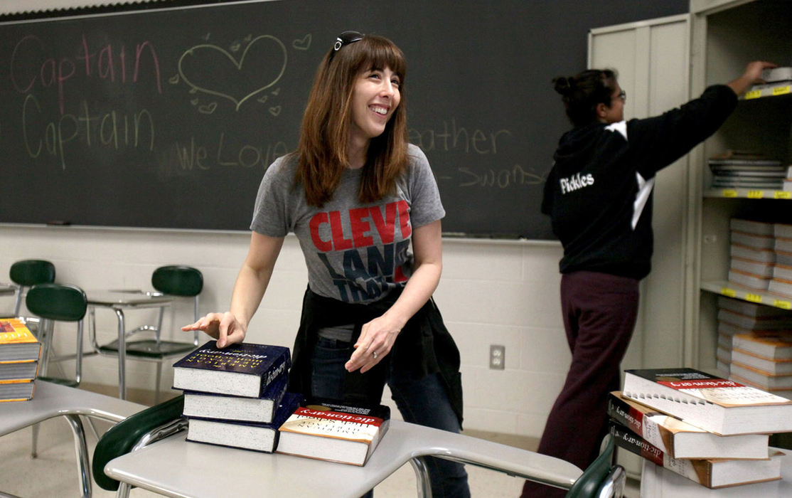 Second Place, News Picture Story - Marvin Fong / The Plain DealerEnglish teacher Heather Keirn-Swanson moves dictionaries inside her Strongsville High School classroom with the help of one of her students Simrit Grewal, 18, senior,  in late April.   The Strongsville teachers strike was settled over weekend negotiations, and instructors were allowed back into their schools Monday afternoon.  Swanson was greeted with symbols and words of appreciation on the back chalkboard.