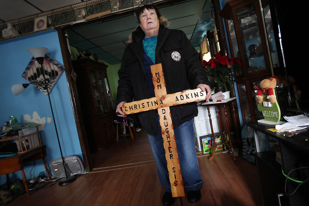 Award of Excellence, News Picture Story - Gus Chan / The Plain DealerMary Adkins holds a wooden cross she'll take to Riverside Cemetery to put on a memorial for her daughter, Christina.  Christina Adkins' body was stuffed in a manhole and her remains went undiscovered for 18 years until her killer, Elias Acevedo, confessed to the crime.
