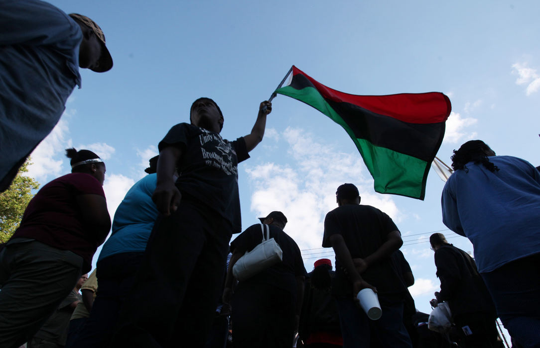 Award of Excellence, News Picture Story - Gus Chan / The Plain DealerA flag is waved by a member of Black on Black Crime during a rally for women's safety in East Cleveland.  Hundreds turned out as family members of three women found murdered in East Cleveland spoke. 