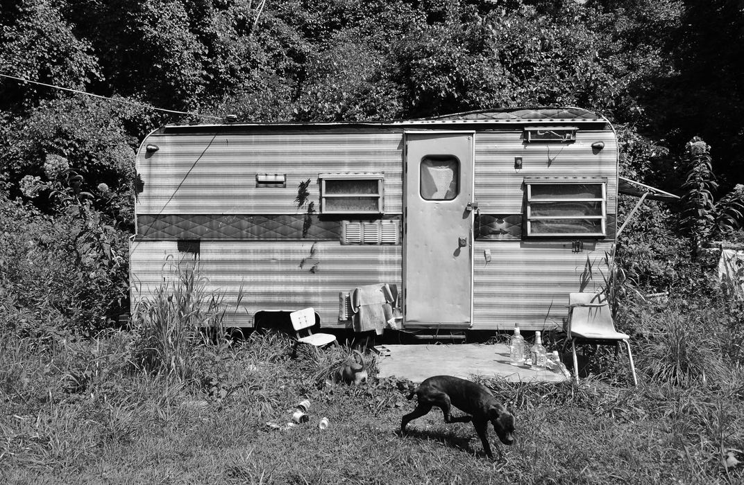 First Place, James R. Gordon Ohio Undertanding Award - Jacob Byk / Kent State UniversityJim Treece’s trailer circa August 2012, with Bingo (Roy “Buckey” Baker’s dog) and another stray dog wandering through the tall weeds. During the next year, Jim contracted cancer and has moved to a care facility elsewhere in the county, leaving his trailer to rot.