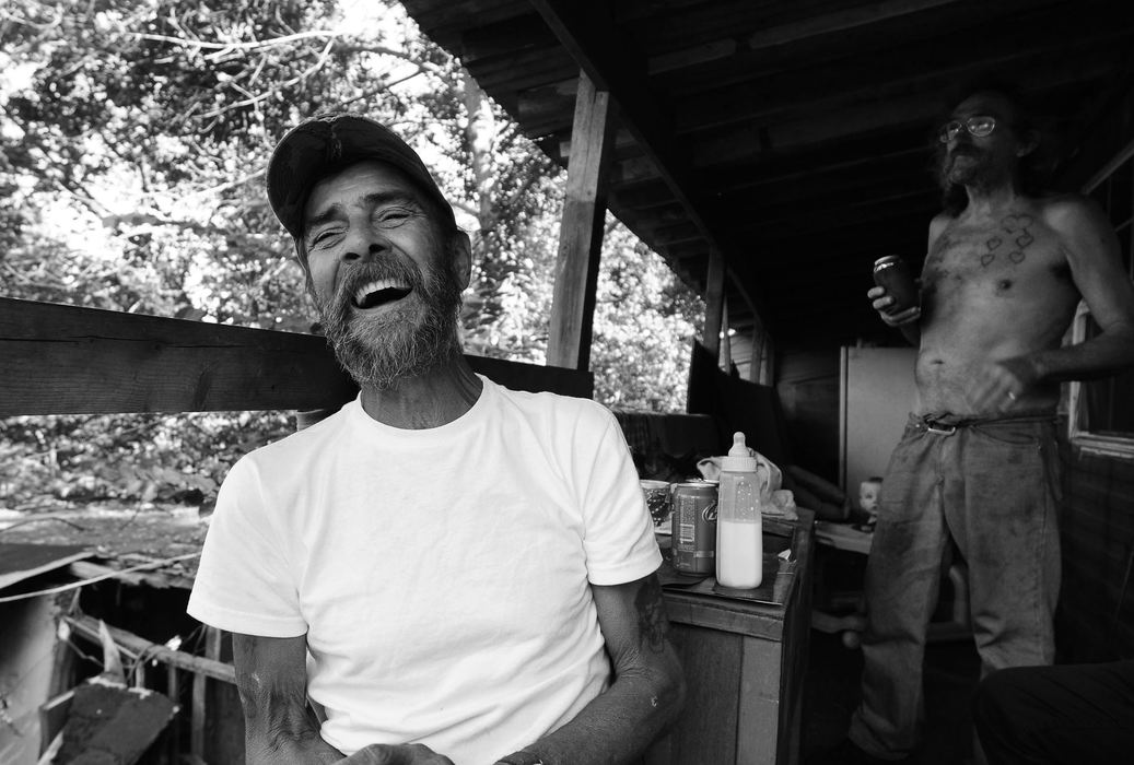 First Place, James R. Gordon Ohio Undertanding Award - Jacob Byk / Kent State UniversityJim Treece, Roy Baker's close friend who leases land from him down the hill, laughs while enjoying beer and good company on a humid afternoon in August 2012 while babysitting, Blake, in the background (Baker's son's son). The retired painter and admitted alcoholic spends his days living in a trailer in shadow of trees and the mountain of shale, at the end of an unpaved gravel road.