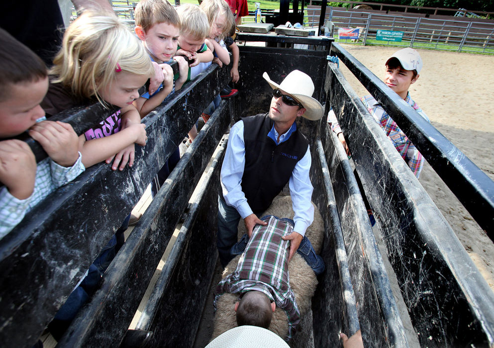 Second Place, Photographer of the Year - Large Market - Lisa DeJong / The Plain Dealer Retired professional bull rider Scott Russell, right, uses Josh Chirdon, 6, of Wadsworth,  to show the kids the correct way to hold onto a sheep for dear life at the Mutton Bustin' School. Very tightly. 