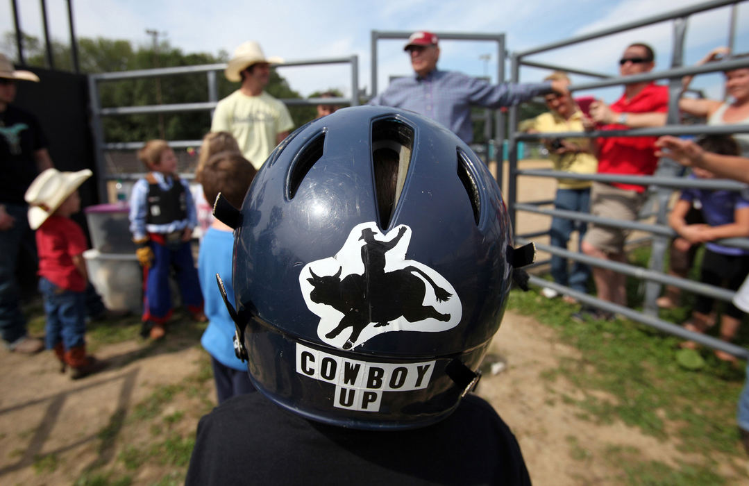 Second Place, Photographer of the Year - Large Market - Lisa DeJong / The Plain DealerThomas Foster, 6, of Wooster, puts on his very own helmet for his first ride of the day at the Mutton Bustin' School.  All riders must wear a helmet and a vest. An aspiring bull rider, Foster is a regular here at Buckin' Ohio and has competed in the Mutton Bustin' portion of their bull riding events. 
