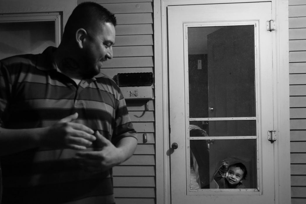 First Place, Photographer of the Year - Large Market - Katie Rausch / The (Toledo) BladeRojelio Sanchez, left, smiles back as his two-year-old son Rojelio III, peers through a hole in the screen door at the family's home in Napoleon. Since being released from prison after serving 11 years for attempted murder, Rojelio has made it his goal to provide a better life for his family. He and his wife Rebecca recently relocated their family of six from North Toledo to Napoleon. Sanchez works as the manager of Evergreen Seed Supply, where he does everything from managing the warehouse, to administrative work to truck driving.   