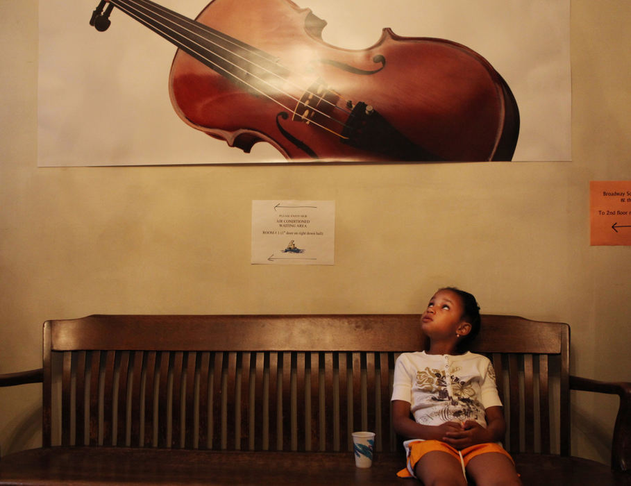 , Photographer of the Year - Large Market - Gus Chan / The Plain DealerBroadway School of Music is located in the Slavic Village neighborhood of Cleveland, a neighborhood considered ground zero in the nation’s foreclosure crisis.  The mission of the school is to provide one-on-one quality music instruction to the community.Enya Blue, 6, sits on the bench while waiting for her Suzuki violin lesson at Broadway School of Music.  Blue is one of five homeschooled children in her family that take music lessons.  She is the fourth child. 