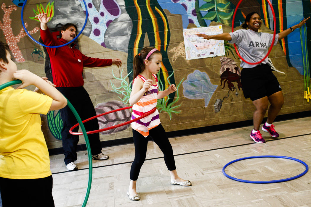 First Place, Photographer of the Year - Small Market - Joshua A. Bickel / ThisWeek Community NewsOlivia Lunde, 9, center, hula-hoops with her brother, Alex, 7, left, and father, Jim, second from left, as Army Capt. Angelia Childs, right, leads the family in the exercise during the first Family Fitness Night Apr. 17, 2013 at Goshen Lane Elementary School in Gahanna, Ohio. Capt. Childs and several other military service members led groups in various activities meant to promote a healthy lifestyle.