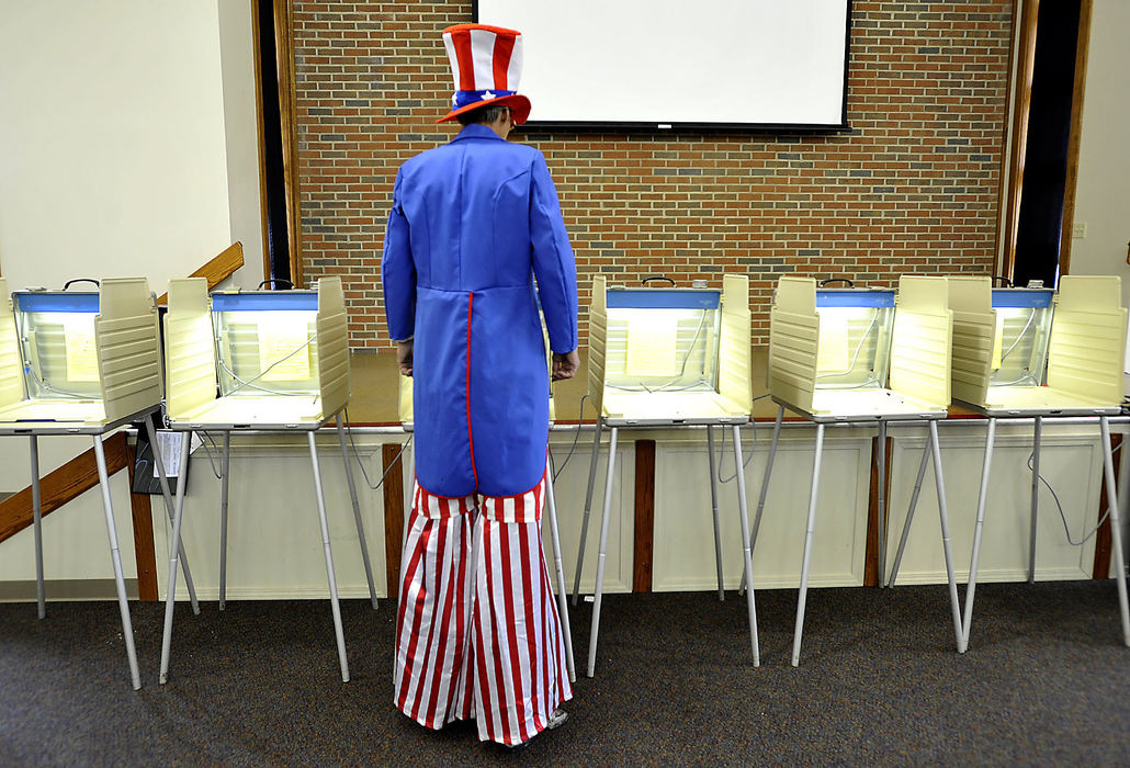 Third Place, Photographer of the year - Small Market - Bill Lackey / Springfield News-SunRick Miller, dressed as Uncle Sam and wearing his drywall stilts, reads the instruction sheet posted in the voting booths at the election poll in the Risen Christ Lutheran Church in Springfield as he waits for voters. Miller said he dresses like Uncle Sam for every election and passes out voting stickers to people after they vote. 