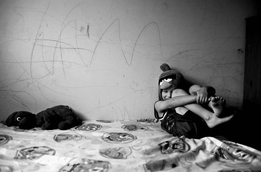 Award of Excellence, Portrait Personality - Kristin Bauer / The (Elyria) Chronicle-TelegramDillon, 6, awaits his family's move in his bedroom at Wilkes Villa.  Dillon's autism has made this move especially difficult, and important throughout the years.  His mother, Tabitha Crabtree, expresses her difficulty in raising a child, let alone an autistic child, as a single mother living in what many call "the projects." There are many scratches and crayon marks left behind above his bed from his outbursts throughout the years.  Throughout the afternoon on move-in day, his family constantly encouraged him that his Spongebob Square Pants bed sheets and his stuffed animal dog will make it to the new house so they could get through the move.