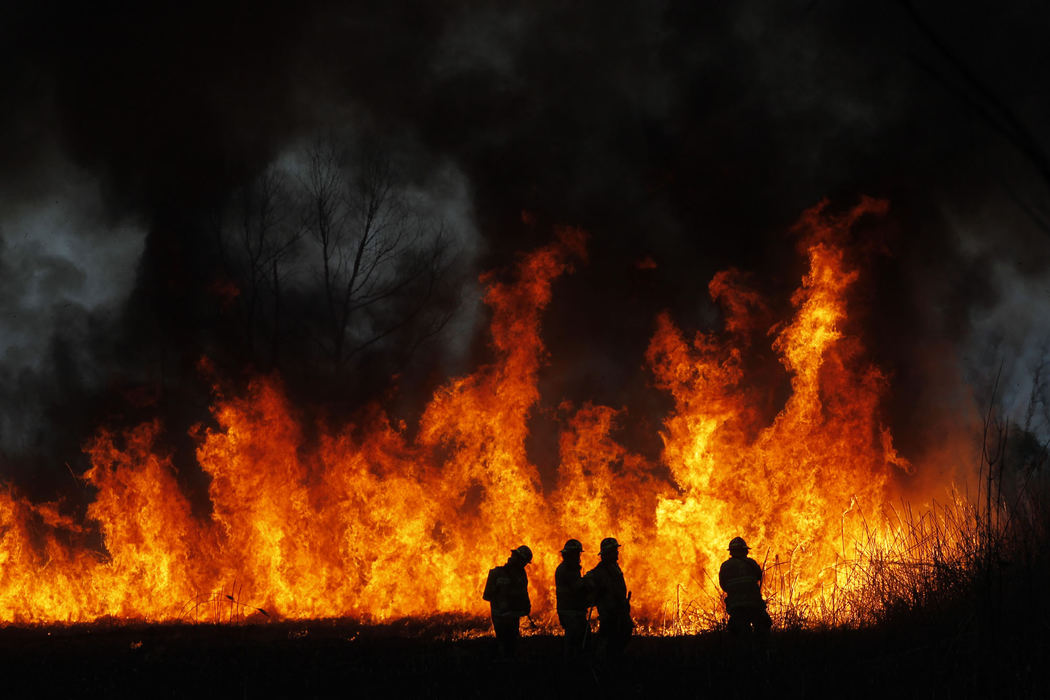 Third Place, Spot News - Large Market - Lori King / The (Toledo) BladeFirefighters are dwarfed by a massive marsh fire in Monroe, Mich. All they could do was watch it burn itself out, considering there was no access for the fire trucks.