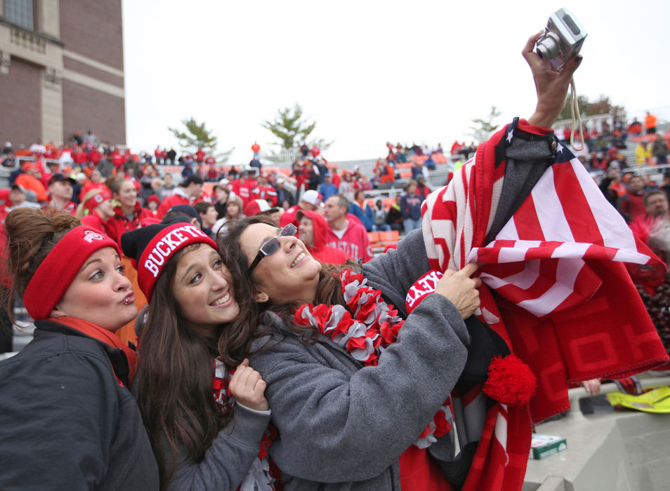 Award of Excellence, Ron Kuntz Sports Photographer of the Year - Chris Russell / The Columbus DispatchBuckeye football fans are fanatics and happy to hit the road to cheer their team on to victory. Ohio State University football fans Allison Zoltanski, Nina Zoltanski and Samantha Zoltanski pose for their own photo in  stands filled with Buckeye fans at Memorial Stadium in Champaign, Illinois on November 16, 2013.  