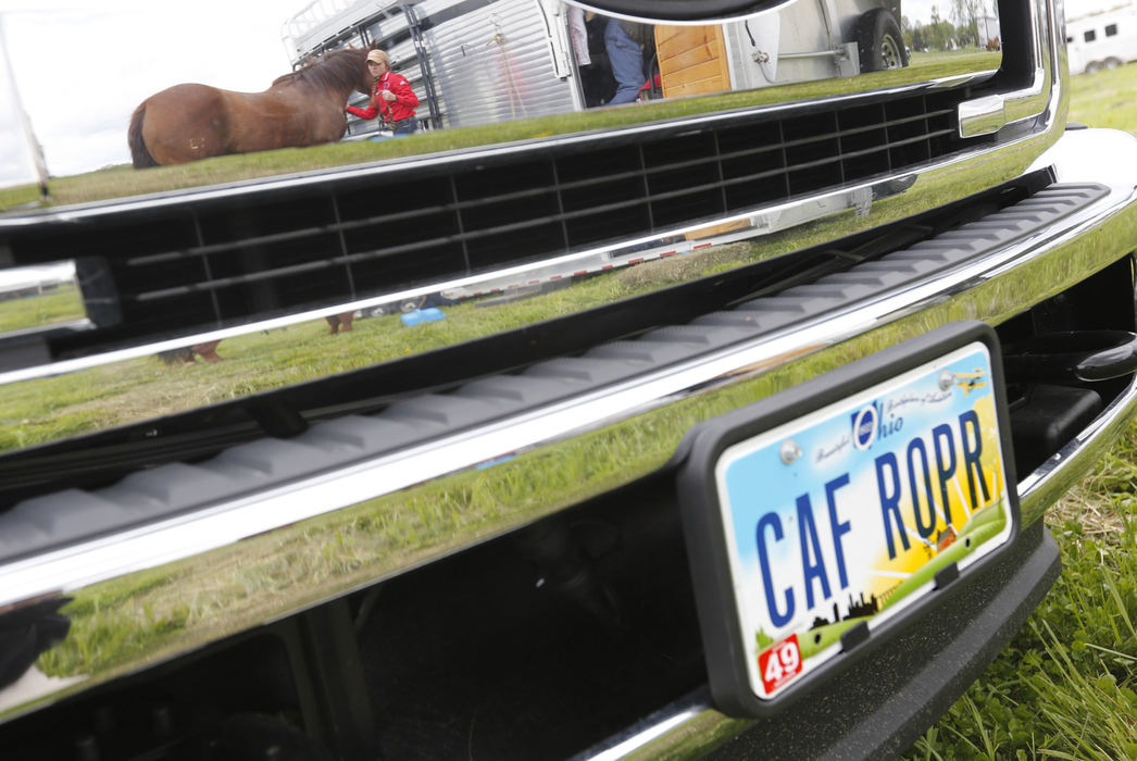 Second Place, Sports Picture Story - Chris Russell / The Columbus Dispatch Josie and Speck are reflected in the chrome bumper of the oversized pickup truck that the family uses to haul the horse trailer and small living quarters they take to each competition. 