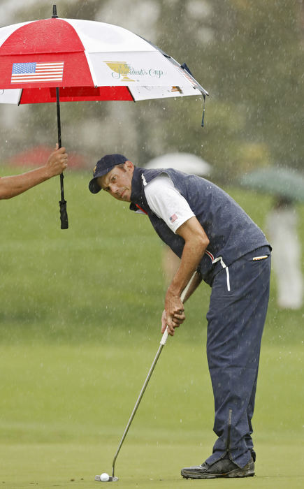 Third Place, Team Picture Story - Chris Russell / The Columbus DispatchMatt Kuchar of the United States Team lines up a putt while his caddy, Lance Bennett tries to keep him dry on the 4th hole during the final  round of the Presidents Cup at Muirfield Village Golf Club in Dublin, Ohio on October 5, 2013.  