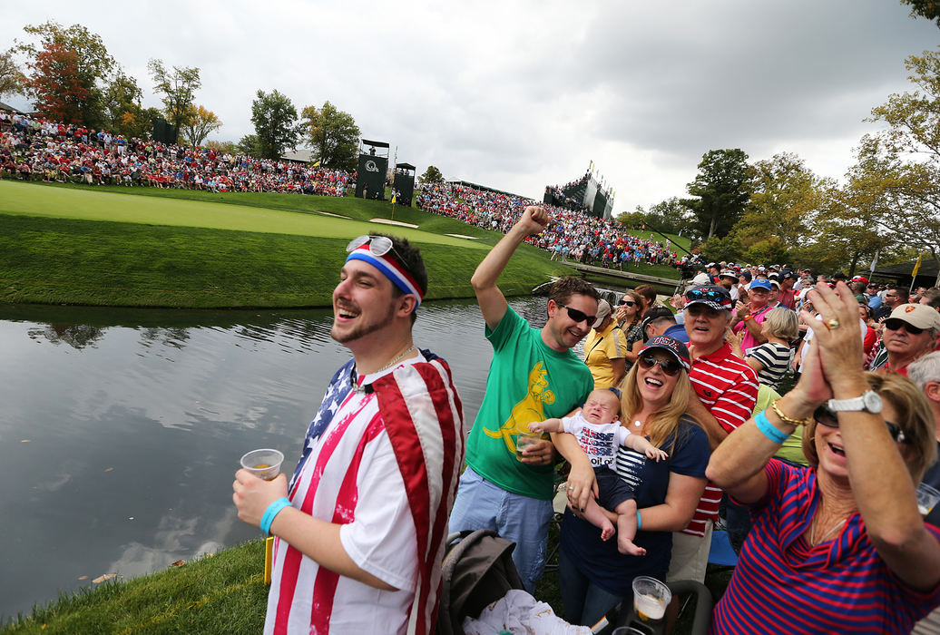 Third Place, Team Picture Story - Eamon Queeney / The Columbus DispatchThe Cox/McCabe family, from Seattle, Wash., reacts as Australian Adam Scott of the International Team's ball lands right next to the hole on the 9th green during the first round of the Presidents Cup at Muirfield Village Golf Club in Dublin, Ohio, Thursday afternoon, October 3, 2013.  At the end of the first round the US Team leads with a score of three and a half to the International Team's two and a half. From left are Marshall McCabe IV, 27;  David Cox, 36;  Cooper Cox, 3 months; Ashley Cox, 31; Marshall McCabe III, 60; and Mary Ann McCabe, 61.     