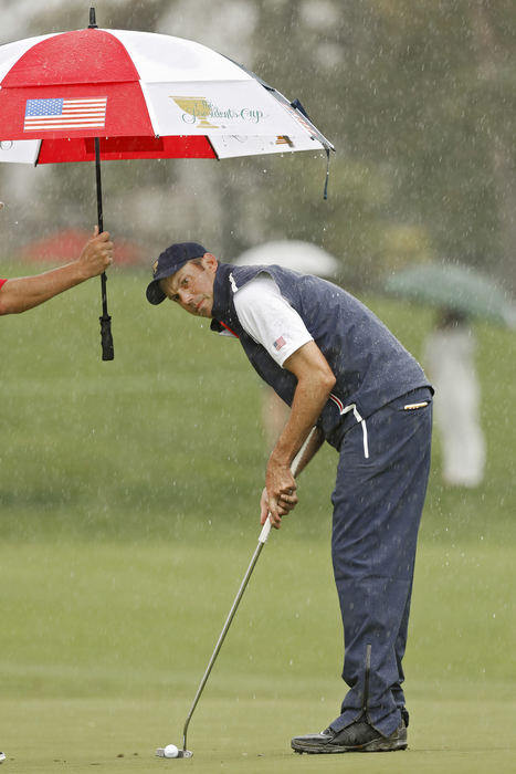 Award of Excellence, Ron Kuntz Sports Photographer of the Year - Chris Russell / The Columbus DispatchMatt Kuchar of the United States Team lines up a putt while his caddy, Lance Bennett tries to keep him dry on the 4th hole during the final  round of the Presidents Cup at Muirfield Village Golf Club in Dublin, Ohio on October 5, 2013.  