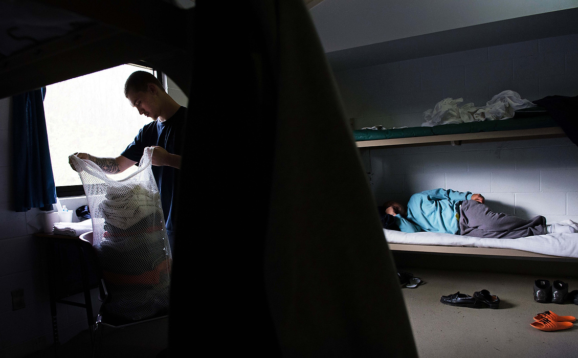 Second Place, Feature Picture Story  - Isaac Hale / Ohio UniversityMichael Hall, left, folds laundry as Mark Bouillion, right, sleeps in their living quarters in the east wing of the facility. The wings of the facility split residents into two groups according to scores on a facility entrance exam. 