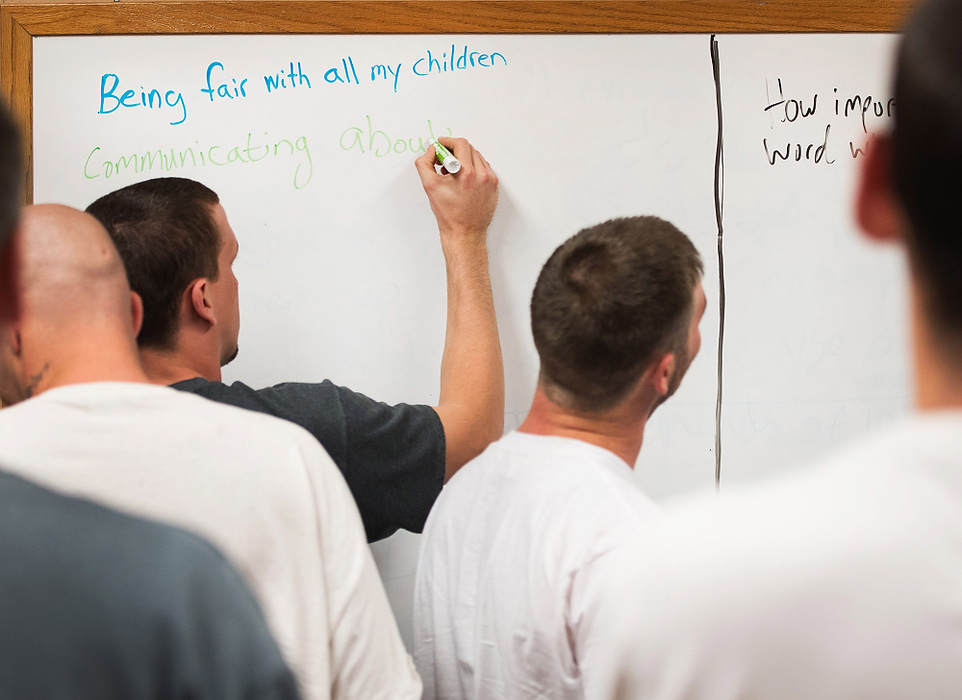 Second Place, Feature Picture Story  - Isaac Hale / Ohio UniversityBradley Bartlett writes something he could improve upon when interacting with his family as other residents wait their turn during a parenting-skills class. Residents were asked to write what skills they could improve upon on the left side of the board and things they had learned from the course on the right side.