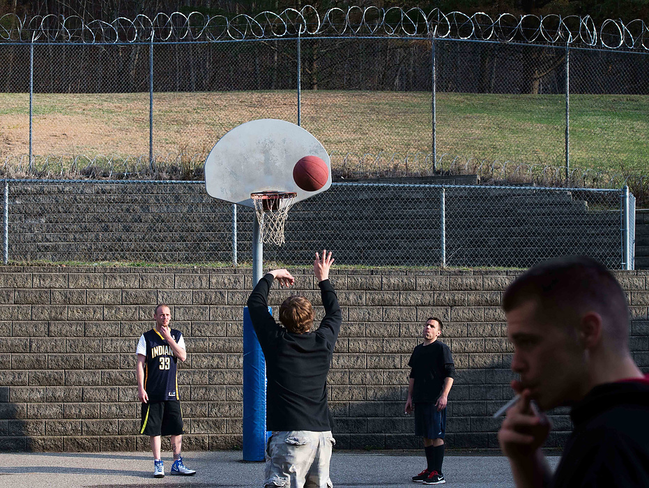 Second Place, Feature Picture Story  - Isaac Hale / Ohio UniversityLucas Reed, center, shoots the basketball during a game of Horse as Phil Stemble, right, and Jared Shumway, left, await the rebound. Troy Jones, foreground, smokes a cigarette, which is a form of currency between the residents.