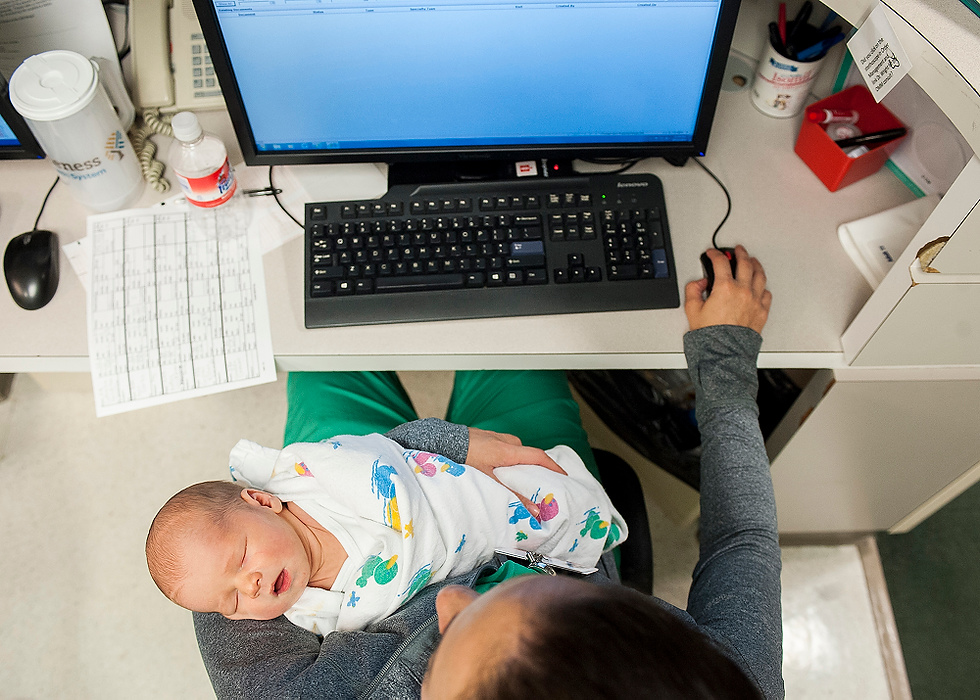 Third Place, Feature Picture Story - Logan Riely / Ohio UniversityDr. Berry cares for a restless two day-old infant while also checking on patients charts while on call. Dr. Berry says, "I chose to do this because it makes me happy. And I haven't found anything else that makes me happier."