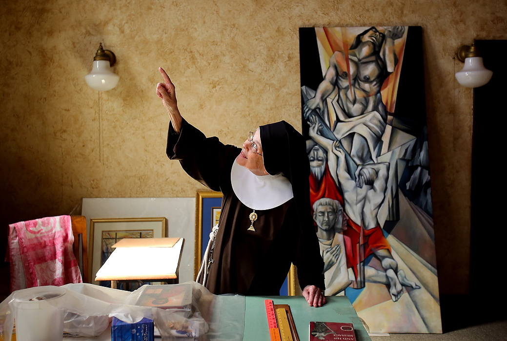 Award of Excellence, Feature Picture Story - Lisa DeJong / The Plain DealerMother Mary Thomas, 81, points to where "God's light" comes into her favorite workroom behind the upper chapel. Behind her is a painting she completed in the 1950s. She actually gave up painting for about 12 years, after she joined the order, until 1972 when she started painting religious themes for the church. 