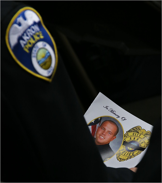 Third Place, News Picture Story - Ed Suba Jr. / Akron Beacon JournalAn Akron police officer looks at the program for the memorial service for Akron Police Officer Justin Winebrenner at the James A. Rhodes Arena in Akron, Ohio. Winebrenner, who was off-duty, was shot and killed at a local bar while trying to break up a fight.