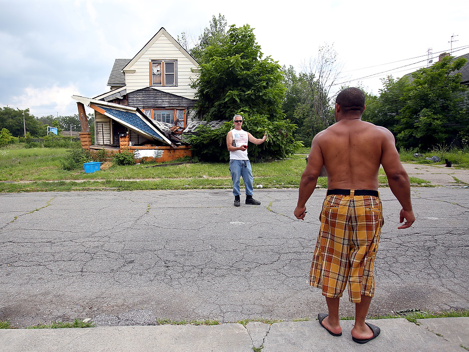 First Place, News Picture Story - Lisa DeJong / The Plain DealerSensing some hostility, Blaine Murphy, left, keeps his distance as he talks with a neighbor who came out to see what Blaine was up to. As the neighbor warmed up to the charming Murphy, he tells Murphy that this porch just caved in last week. The neighbor said the guy abandoned his home just the week before. Blaine gave a Slavic Village Development card to him and to call if he sees more dumping or looting. Blaine Murphy visits this OVV property, or open, vacant and vandalized properties, on his endless code enforcement tours of Slavic Village, part of his community service.   