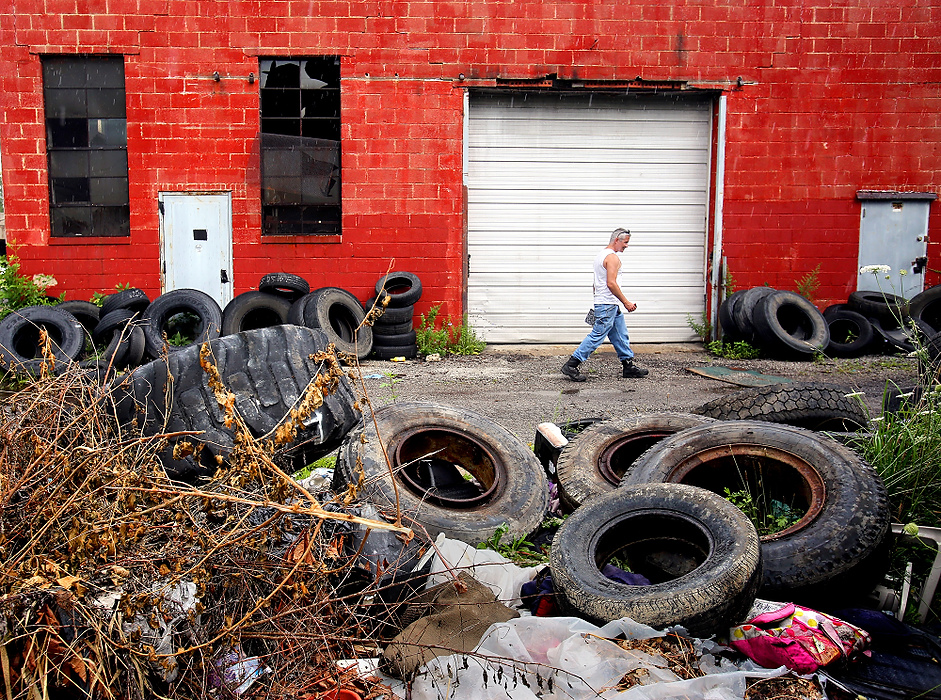 First Place, News Picture Story - Lisa DeJong / The Plain DealerBlaine Murphy walks through illegally dumped tires behind a garage on E. 78th Street. Murphy counts over 100 tires in just one location. This is one of Murphy's stops on his endless code enforcement tours of Slavic Village.