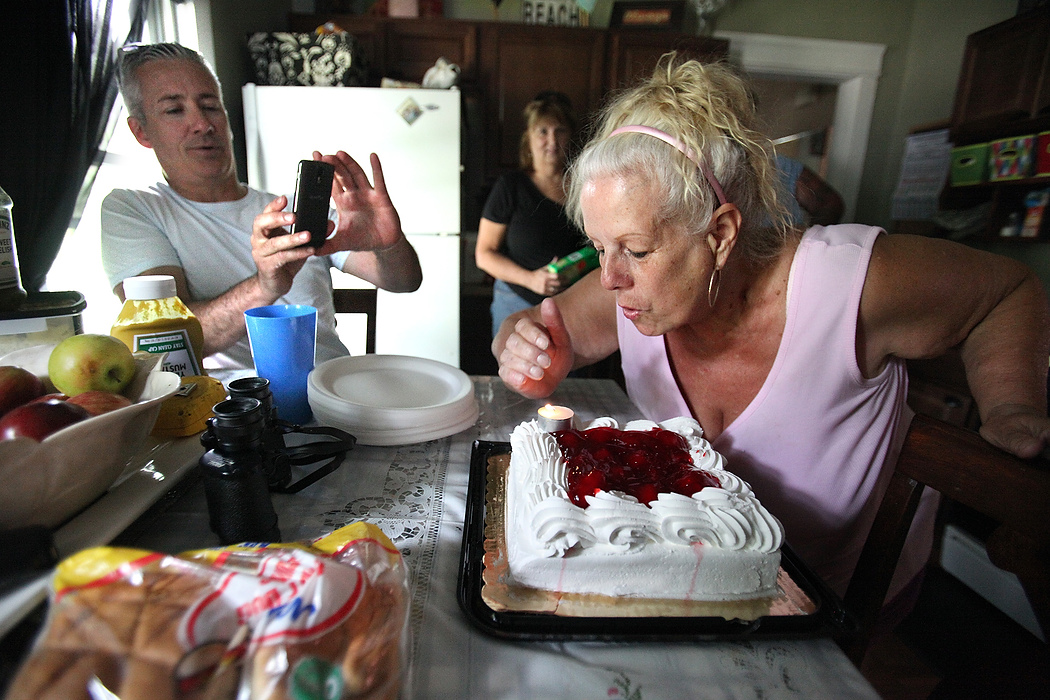 First Place, News Picture Story - Lisa DeJong / The Plain DealerBlaine Murphy, left, takes pictures of neighbor Mary Hess blowing out her birthday candles at Lynda's house. As Slavic Village neighbors surprisingly opened their arms to him, Murphy learned more about their forgiving character then he deserved. Little did Murphy know, Slavic Village needed him just as much as he needed them. Murphy, who lives a couple blocks away, is struck by the ironic friendships with people he now considers family.