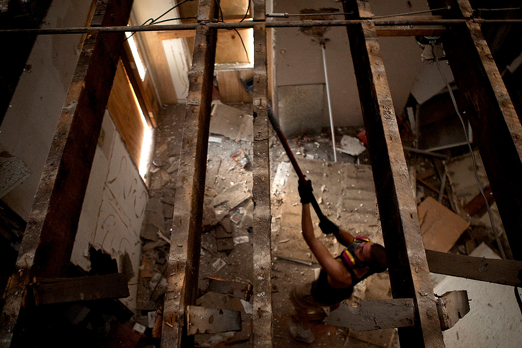 First Place, James R. Gordon Ohio Understanding Award - Jessica Phelps / Newark AdvocateJeremy Miller tears down ceiling beams from an abandoned house on Dakota Ave to salvage for future projects. Miller and many others see this as a way to recycle old materials and save money. 