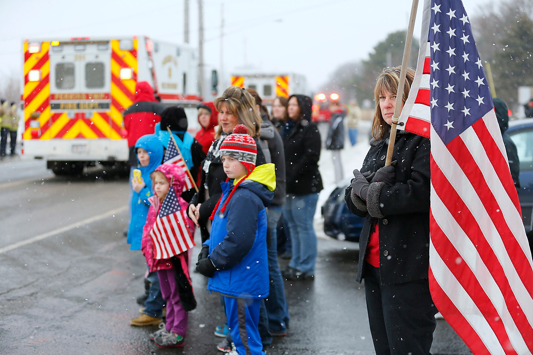 Third Place, Photographer of the Year - Large Market - Andy Morrison / The (Toledo) BladeKim Cowie, Sandusky, holds a flag as she and others stand in front of Perkins Fire Station 2, where Toledo firefighter James Dickman used to work, as the funeral processes to Oakland Cemetery.