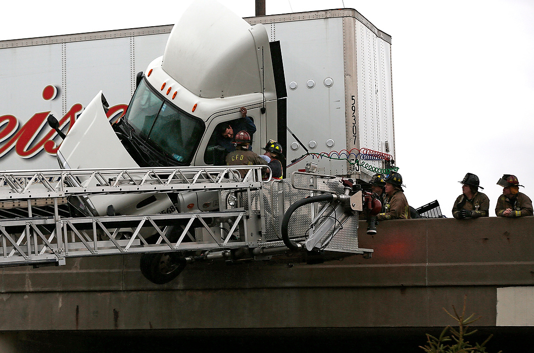 First Place, Photographer of the Year - Large Market - Eamon Queeney / The Columbus DispatchA truck driver is pulled out of cab by Columbus fire fighters as it dangles on the edge of the 315 north-bound bridge over Sullivant Avenue on the West Side of Columbus. The north-bound lanes of 315 had to be closed as emergency responders worked to save the driver of a crashed semi trailer. 