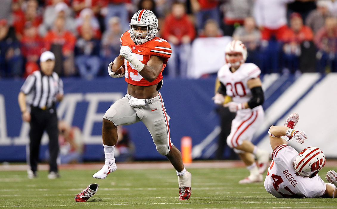 First Place, Photographer of the Year - Large Market - Eamon Queeney / The Columbus DispatchOhio State running back Ezekiel Elliott (15) runs out of his shoe in the fourth quarter of the Big Ten Championship game against Wisconsin at Lucas Oil Stadium in Indianapolis. Ohio State Buckeyes went on to shock the nation by defeating the Badgers 59 - 0.