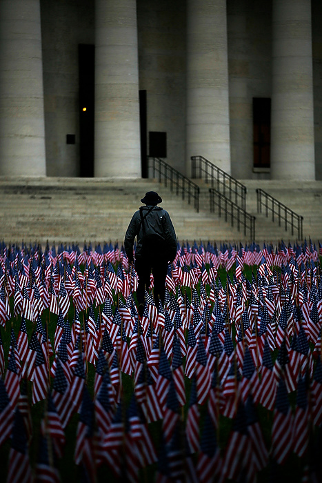 First Place, Photographer of the Year - Large Market - Eamon Queeney / The Columbus DispatchDaniel Thomas, of Upper Arlington, walks through a September 11th memorial on the Ohio Statehouse lawn after taking a photograph. The lawn was covered with 2,999 American flags today to honor each life lost in the attacks on the United States on September 11, 2001. They were arranged in two columns to represent the twin towers with a pentagon-shaped cutout in the center.  