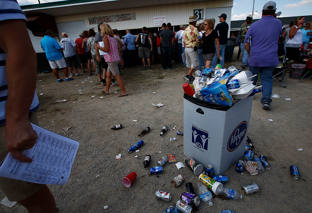 First Place, Photographer of the Year - Large Market - Eamon Queeney / The Columbus DispatchA trashcan overflows with empty beer cans and bottles as race goers line up to place bets during the 69th running of the Little Brown Jug at the Delaware County Fairgrounds. Yannick Gingras driving Limelight Beach won the Little Brown Jug. 