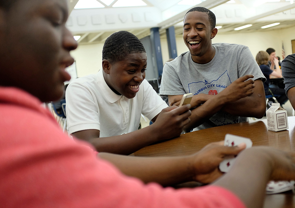 First Place, Photographer of the Year - Large Market - Eamon Queeney / The Columbus DispatchSenior Ronnie Williams (right) and sophomore Nyshawn Ramsey (center) laugh at something on Ronnie's phone between hands in a game of cards with senior Netronne Backus (left) during lunch.