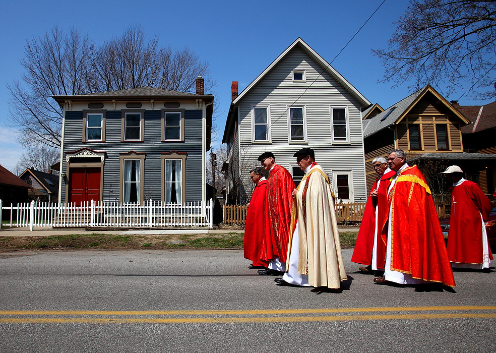 Second Place, Photographer of the Year - Large Market -  Lisa DeJong / The Plain DealerPriests lead the procession as they walk down Bridge Avenue in Ohio City during the annual Good Friday procession in Cleveland. The annual 3-mile procession shows the unity of the Hispanic Catholic community. The procession started at noon at St. Michael the Archangel Church on Scranton Road, where hundreds of people walked through the streets of Ohio City to St. Patrick church for a reading from The Gospel.  The procession then walked to La Sagrada Familia on Detroit Avenue for the homily, adoration of the cross and a communion service. 