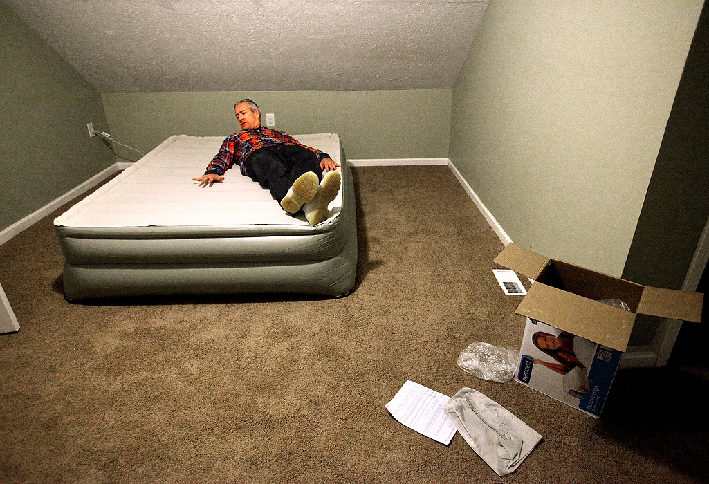 Second Place, Photographer of the Year - Large Market - Lisa DeJong / The Plain Dealer***PLEASE read synopsis from RTF file. It cuts it off here in caption block *** Just hours after being released from prison in January, Blaine Murphy, 46, tries out his new air mattress he just got from Target in his frigid upstairs bedroom at the house where he will live for the next 18 months in the Slavic Village neighborhood.  Judge Richard McMonagle released Murphy today to serve the remainder of his 18-month prison term from a fixed-up home he owns on Beyerle Road in Slavic Village. Until he completes 3,000 hours of community service - the equivalent of a full time job for the next 18 months - and pays his remaining $250,000 in restitution, he will be shackled to Slavic Village. A proud, working-class neighborhood still anchored with original Polish immigrants, Slavic Village is straining to recover from the foreclosure crisis, an unnatural disaster that left it littered with thousands of vacant and abandoned homes. Murphy made the neighborhood worse, according to prosecutors. Murphy's crimes involved buying hundreds of rundown homes sight-unseen from banks then flipping them to another buyer at a profit, ignoring code violations and failing to pay taxes. The homes would often sit vacant, contributing to neighborhood decay and acting as magnets for crime. Murphy begged to go back to prison instead of living among the people who would blame him for their ruined neighborhood. He feared for his safety. Worse yet, McMonagle wanted Murphy to answer to Tony Brancatelli, the Cleveland councilman elected to serve the area.  Brancatelli publicly painted him as a careless carpetbagger who greedily scooped up properties in the neighborhood, only to let them rot. Little did Murphy know, Slavic Village needed him just as much as he needed them. As Slavic Village neighbors surprisingly opened their arms to him, Murphy learned more about their forgiving character then he thought he deserved. Long-time neighborhood activists like Lynda Lewis knew Murphy was the catalyst Sla