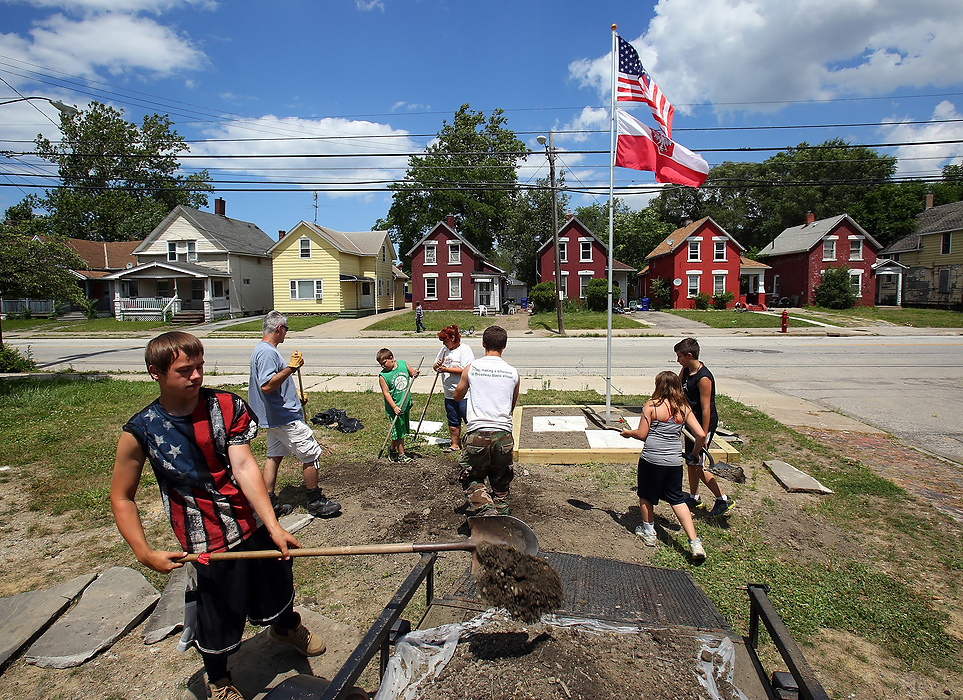 Second Place, Photographer of the Year - Large Market - Lisa DeJong / The Plain DealerLittle did Murphy know, Slavic Village needed him just as much as he needed them. Long-time neighborhood activists like Lynda Lewis knew Murphy was the catalyst Slavic Village craved. Blaine Murphy and some neighbors have tried to turn this vacant corner lot into a tiny park, erecting a flagpole and building a walking path to a seated area. Vandals keep coming back, time after time, destroying  the flagpole as well as defacing the stones with graffiti. Knowing they were on borrowed time, Lewis and Murphy started the momentum by boarding up houses, cleaning up over 2,000 tires, hauling away dumpsters of junk from vacant homes, creating parks, planting trees.  Life-long friendships blossomed. 