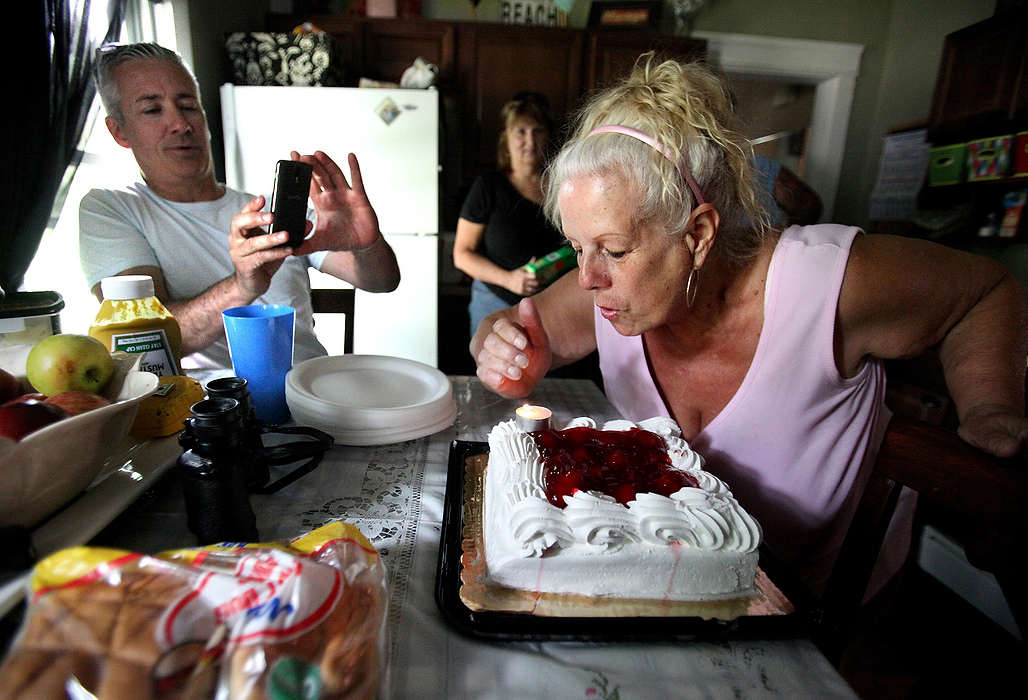 Second Place, Photographer of the Year - Large Market - Lisa DeJong / The Plain DealerBlaine Murphy, left, takes pictures of neighbor Mary Hess blowing out her birthday candles at Lynda's house. As Slavic Village neighbors surprisingly opened their arms to him, Murphy learned more about their forgiving character then he deserved. Little did Murphy know, Slavic Village needed him just as much as he needed them. Murphy, who lives a couple blocks away, is struck by the ironic friendships with people he now considers family.